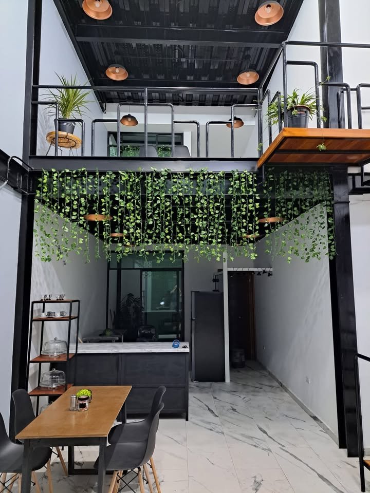 Interior de Margo Café: mezzanine de acero con vid colgante y luces de cobre